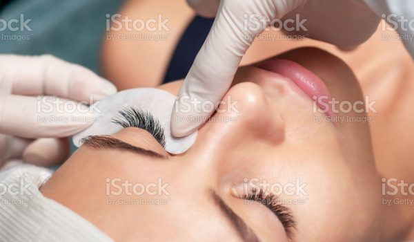 Young woman receiving extending the eyelashes in a beauty salon, close up, eyelash extension procedure.