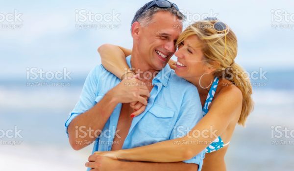 Mature couple relaxing on beach sitting on beach towel with the ocean in the background. Santa Rosa Beach, Florida