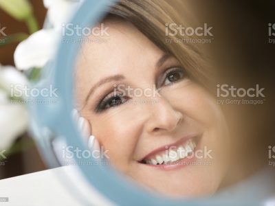 Happy mature woman looking in the mirror. Close-up