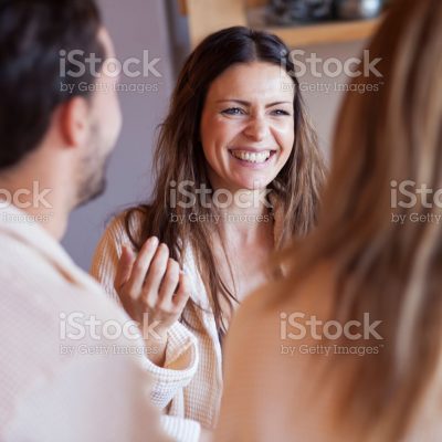 People in bathrobes having fun, talking, smiling. Mid adult woman - mother in focus.